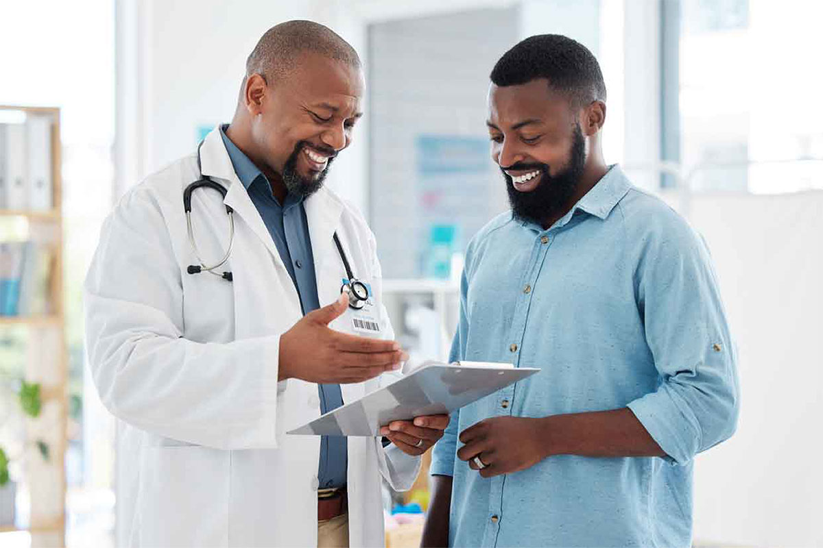 Male doctor looking at a chart with a male patient both smiling